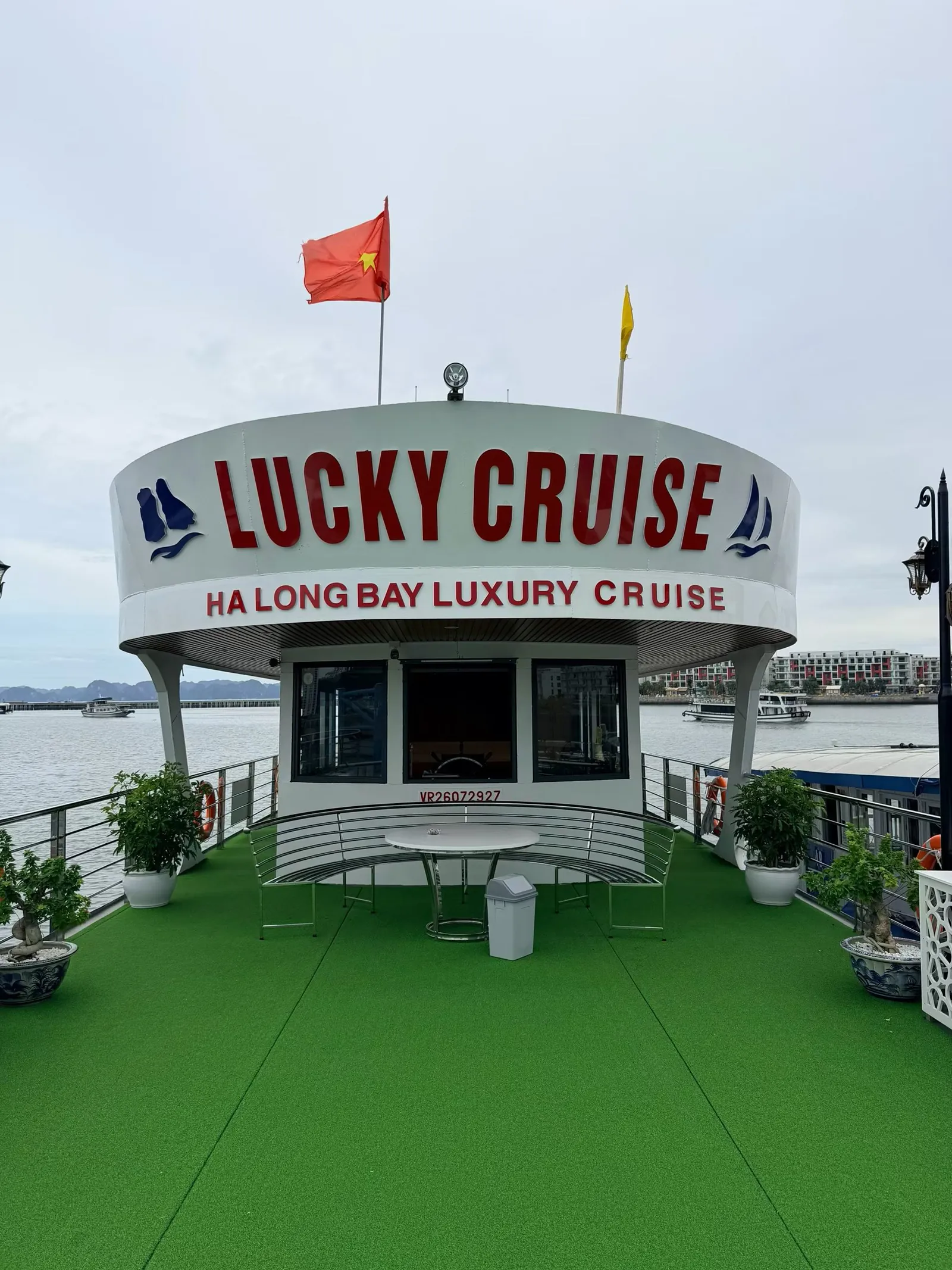 下龙湾游船甲板,绿色人工草坪上方是写着 LUCKY CRUISE 的船舱,旗杆上飘着越南国旗